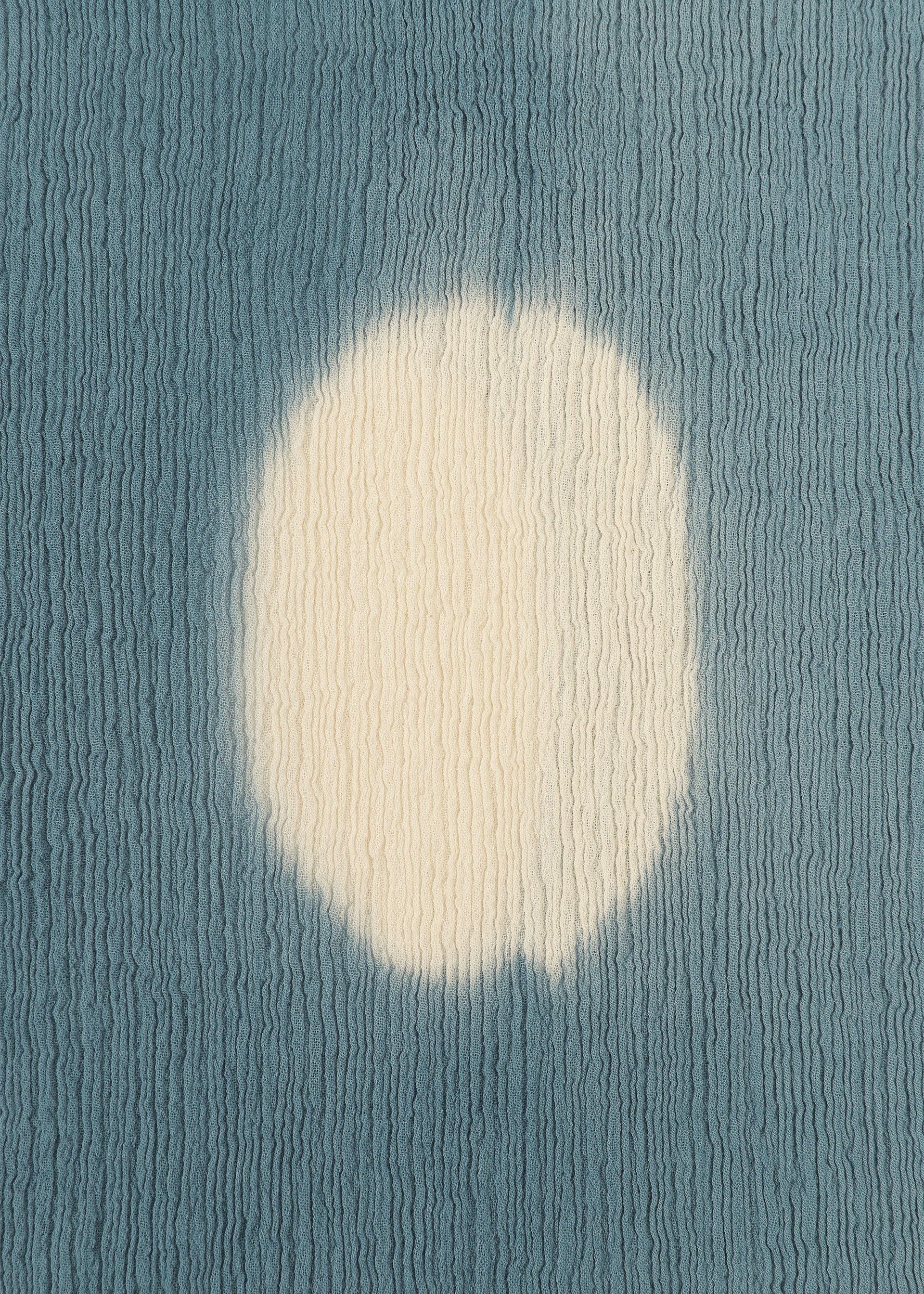 Zoomed view The KYO CHIJIMI ITAJIME by HaaT features a textured blue surface with a large, irregular white circle at the center, evoking Itajime dyeing on handcrafted skirts, set against a wavy ridged background.
