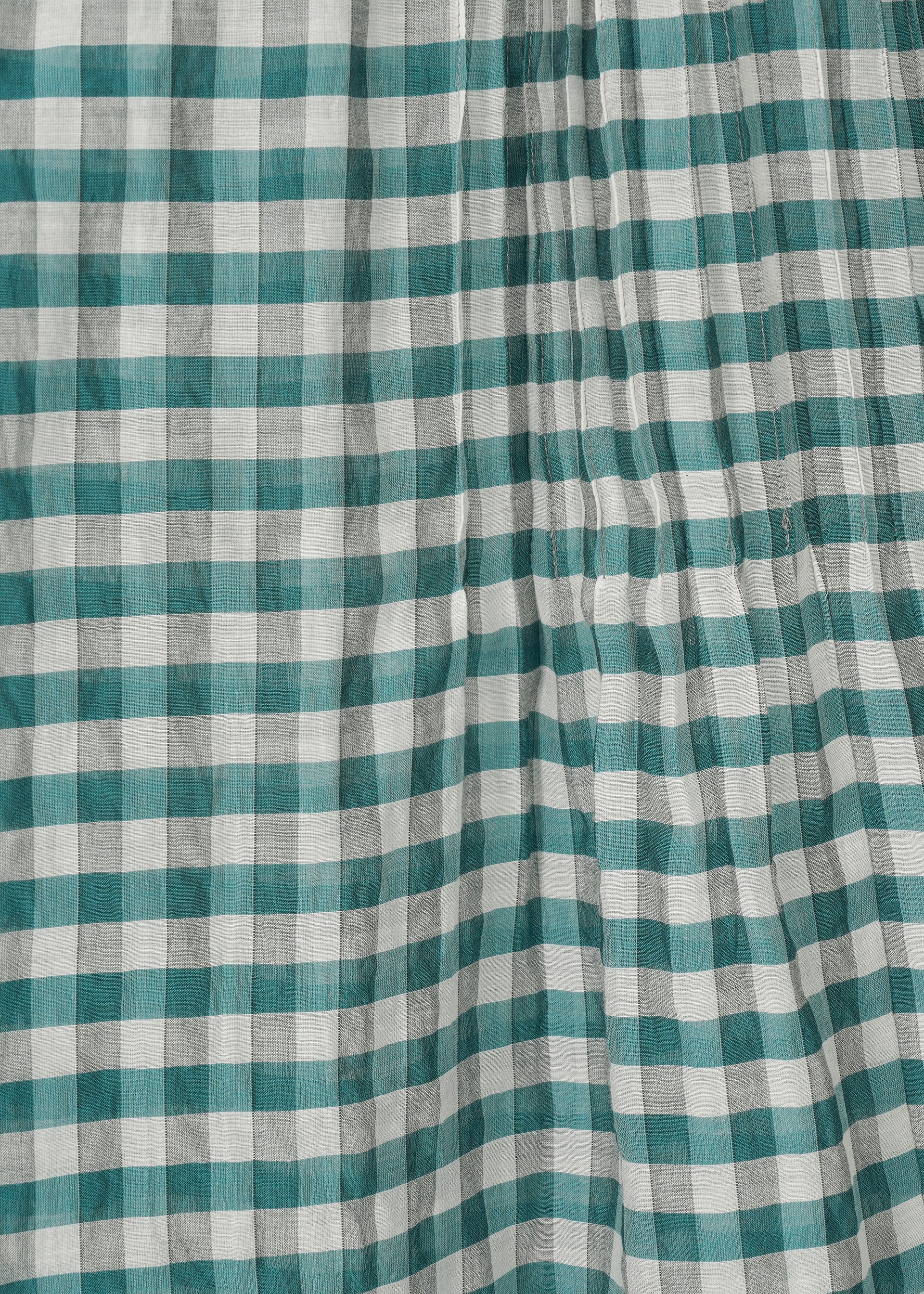 Zoomed view A close-up of HaaT's 2 SIDE PINTUCKING shows green and white checkered fabric with a wrinkled texture, featuring classic gingham stripes in an alternating horizontal and vertical pattern.