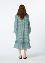 A person with long, curly hair stands facing away, wearing the HaaT 2 SIDE PINTUCKING dress and black sandals against a plain light background.