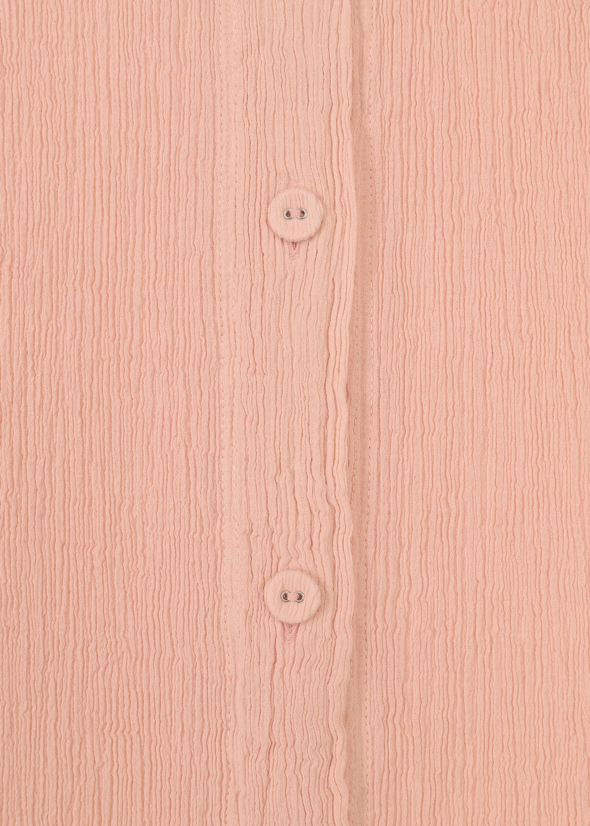 Close-up of pink textured fabric with vertical ridges from the HaaT KYO CHIJIMI FEBRUARY dress, featuring two round pink buttons aligned vertically down the center. view 5 of 8