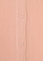 Close-up of pink textured fabric with vertical ridges from the HaaT KYO CHIJIMI FEBRUARY dress, featuring two round pink buttons aligned vertically down the center.