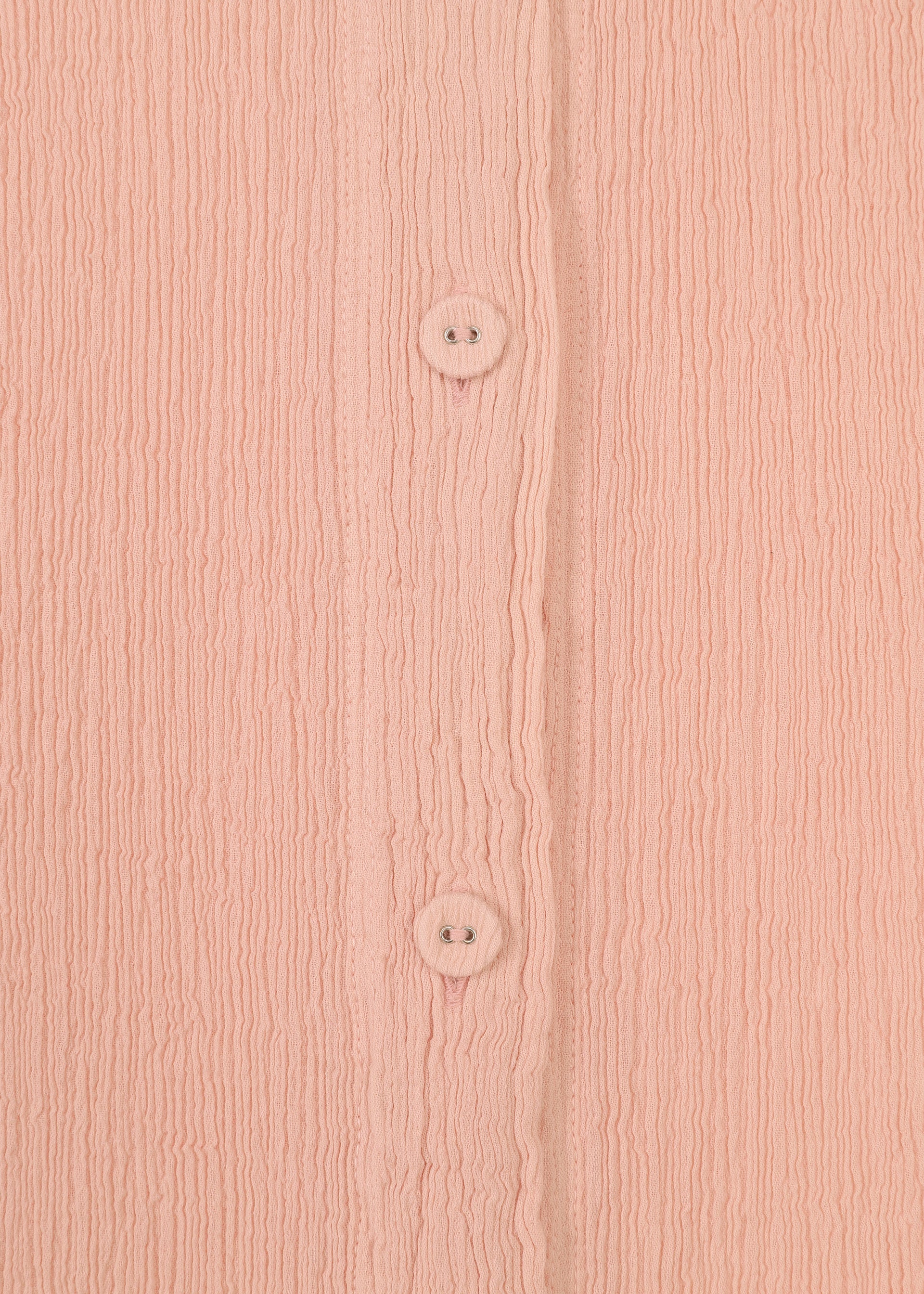 Zoomed view Close-up of pink textured fabric with vertical ridges from the HaaT KYO CHIJIMI FEBRUARY dress, featuring two round pink buttons aligned vertically down the center.