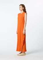 Against a white background, a woman wears the HaaT KYO CHIJIMI MAY sleeveless orange dress, crafted from ultra-fine cotton for lightweight comfort, paired with beige textured slip-on shoes as she faces slightly right.