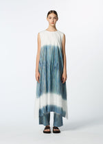 A person stands facing forward wearing HaaT's SAZANAMI—a sleeveless, flowing hand-painted dress with blue, green, and teal vertical streaks—over matching pants and black sandals against a plain light background.