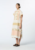 A woman in the HaaT KASANEGAKE jacquard dress with pastel pink, white, and yellow bands and frayed edges stands sideways, her hair slicked back and wearing black sandals against a plain white background.