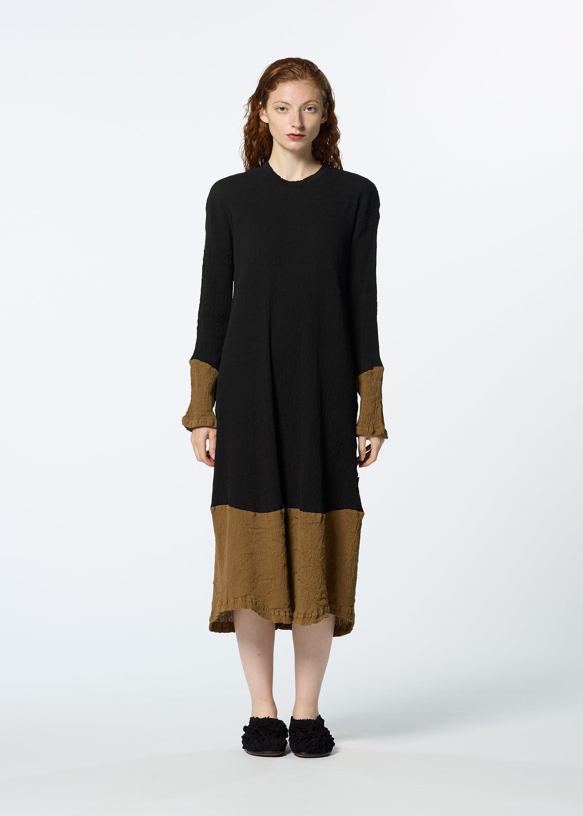 A woman with wavy reddish-brown hair stands facing forward in a HaaT KYO CHIJIMI STREAM dress—black top, brown sleeves and hem—with black shoes, set against a plain white background. view 4 of 6