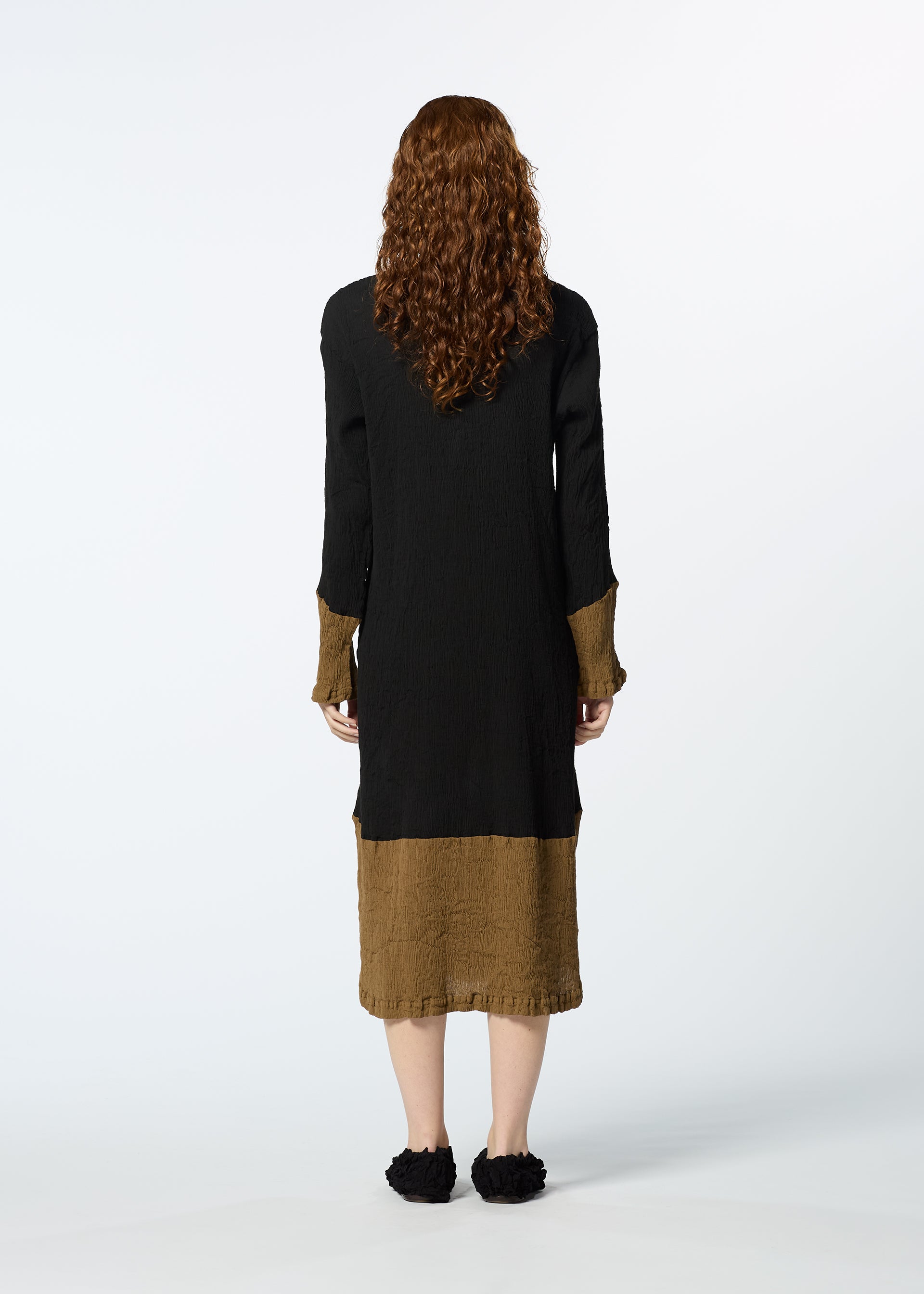 Zoomed view A person with long curly hair models the HaaT KYO CHIJIMI STREAM dress, featuring black and brown contrasting colors, while standing with their back to the camera against a plain white background.