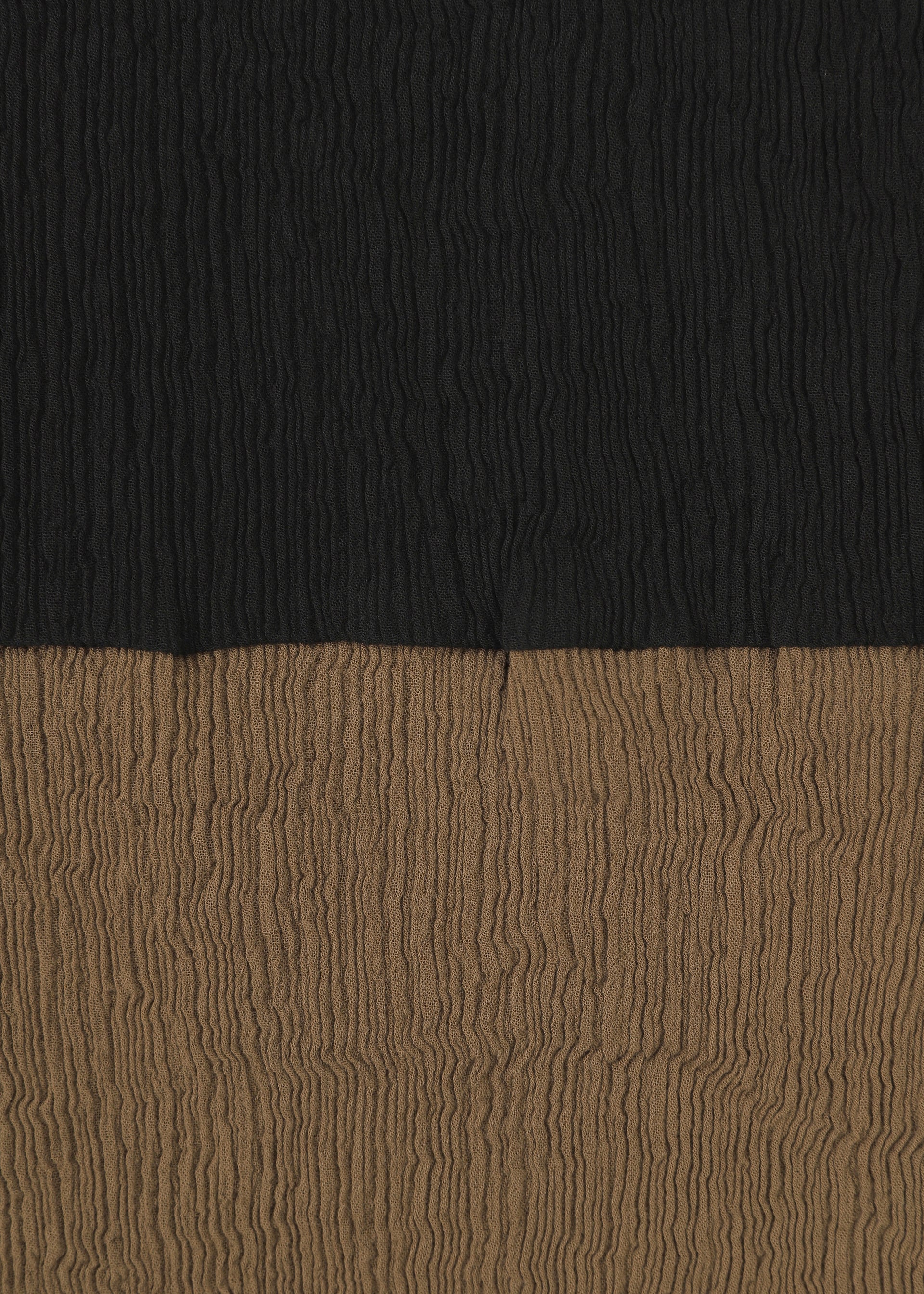 Zoomed view The HaaT KYO CHIJIMI STREAM features textured fabric with horizontal, crinkled lines and two-tone color blocking: black on the upper half and brown on the lower half.