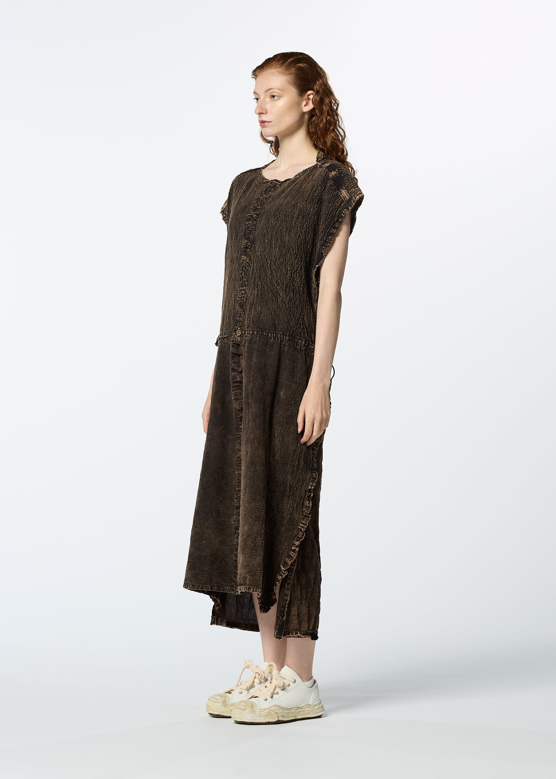Zoomed view A person with long, wavy red hair wears the HaaT TENMOKU COTTON loose dark brown textured dress with short sleeves and frayed edges, paired with white sneakers, standing against a plain light background.