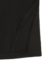 Close-up of TENMOKU COTTON by HaaT, a black fabric with a folded corner and ruffled edge. The smooth, subtly textured surface displays slight variations, reminiscent of garment-dyeing for added depth.