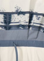 Close-up of the KASANEGAKE by HaaT: textured fabric with horizontal blue stripes and abstract blue patterns on white. Features a blue drawstring at the bottom, highlighting its layered design.