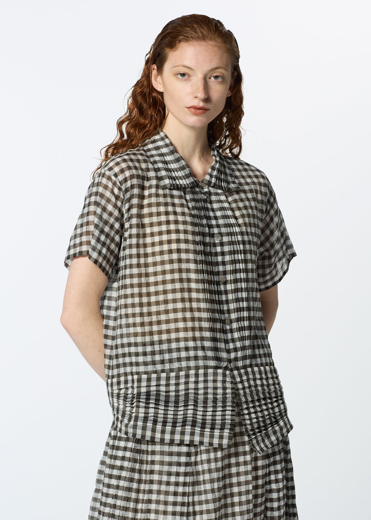 A person with long, wavy red hair models HaaT’s 2 SIDE PINTUCKING short-sleeved black and white gingham shirt and matching skirt, standing against a plain white background. view 9 of 9