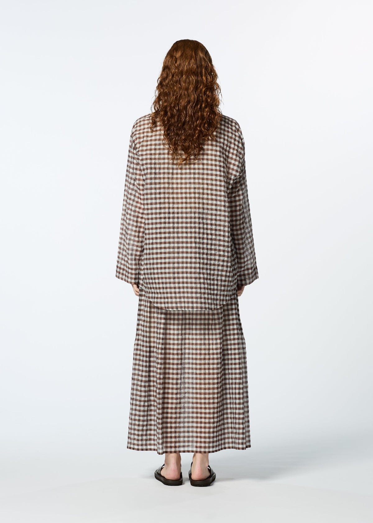 A person with long curly hair models HaaT's 2 SIDE PINTUCKING brown and beige gingham cotton-silk blend long-sleeve shirt and matching skirt, standing with their back to the camera against a white background. view 8 of 8
