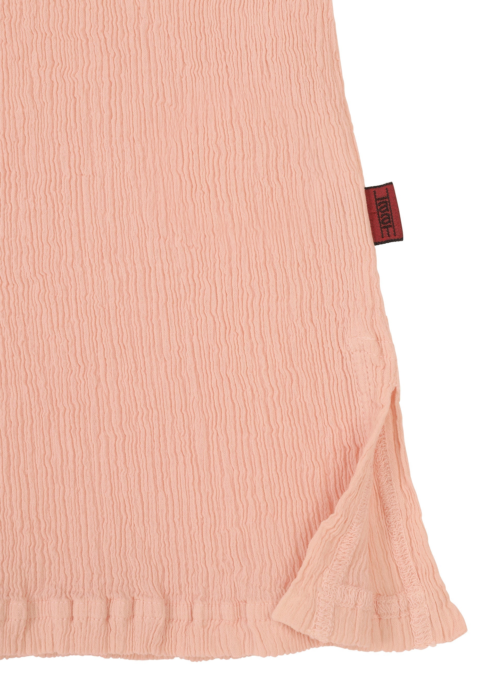 Zoomed view A close-up of KYO CHIJIMI FEBRUARY by HaaT shows light pink, crinkled fabric with a hem slit and a dark red side tag—ideal for an ultra-fine cotton round-neck top.