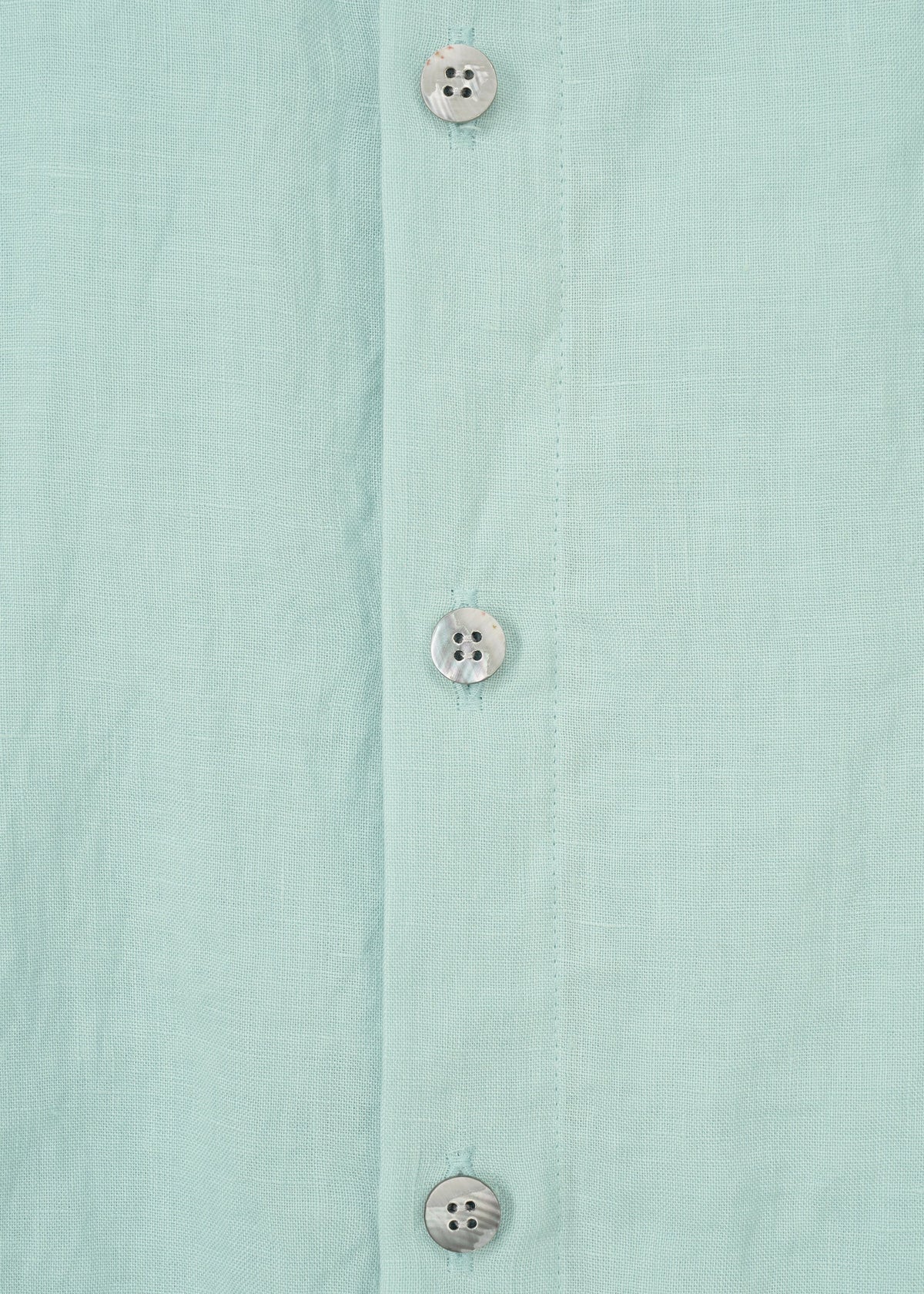 Close-up of the JIKI blouse by HaaT: a light blue women's top made from French linen, featuring three white plastic buttons on the vertical placket. view 5 of 8