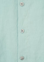 Close-up of the JIKI blouse by HaaT: a light blue women's top made from French linen, featuring three white plastic buttons on the vertical placket.