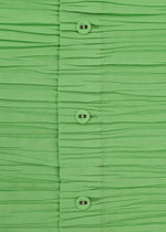 Close-up of the SHIBARI SHIRT by HaaT—bright green, short-sleeved, with horizontal pleats and a row of green buttons down the center, crafted from recycled polyester.