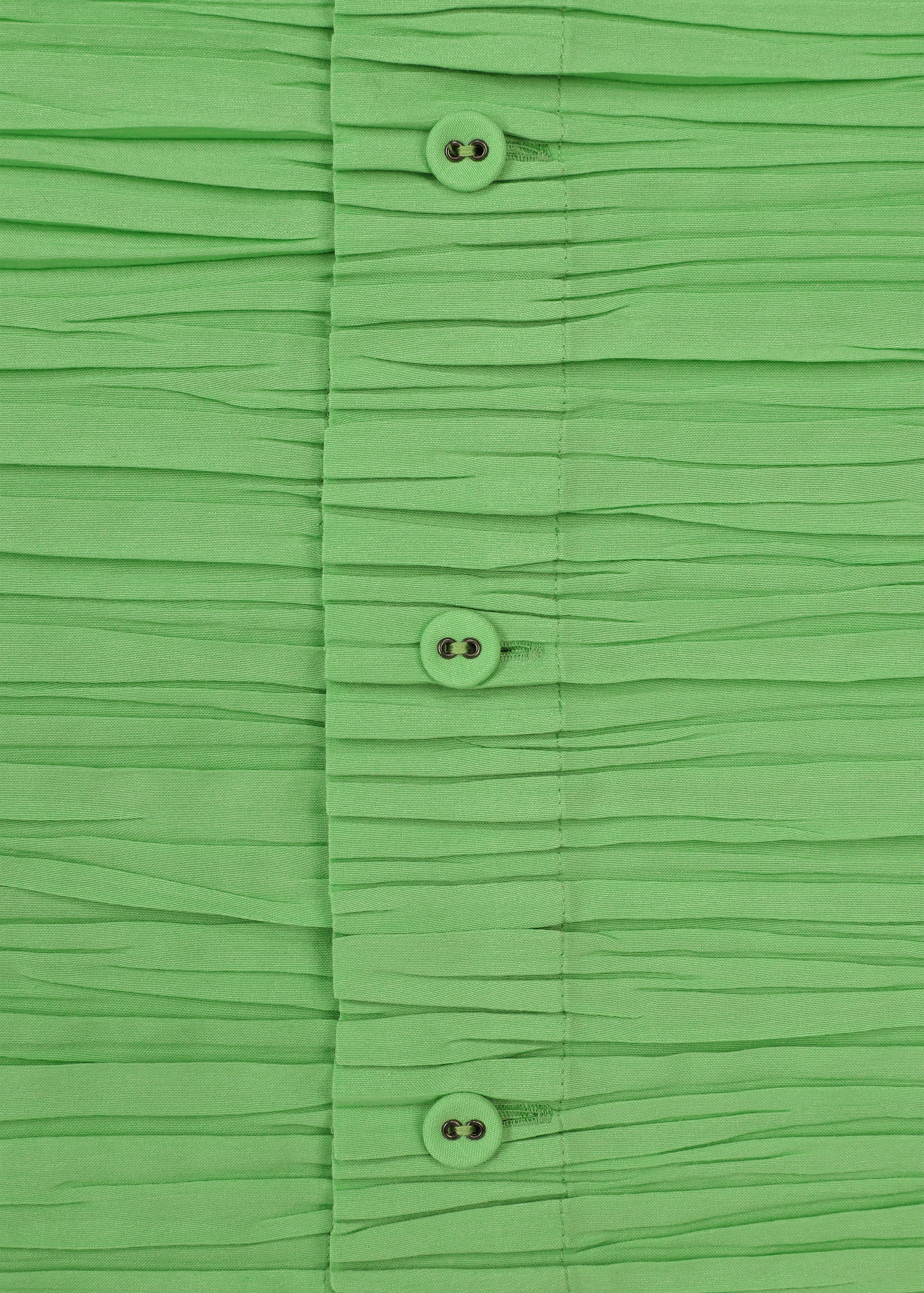 Zoomed view Close-up of the SHIBARI SHIRT by HaaT—bright green, short-sleeved, with horizontal pleats and a row of green buttons down the center, crafted from recycled polyester.
