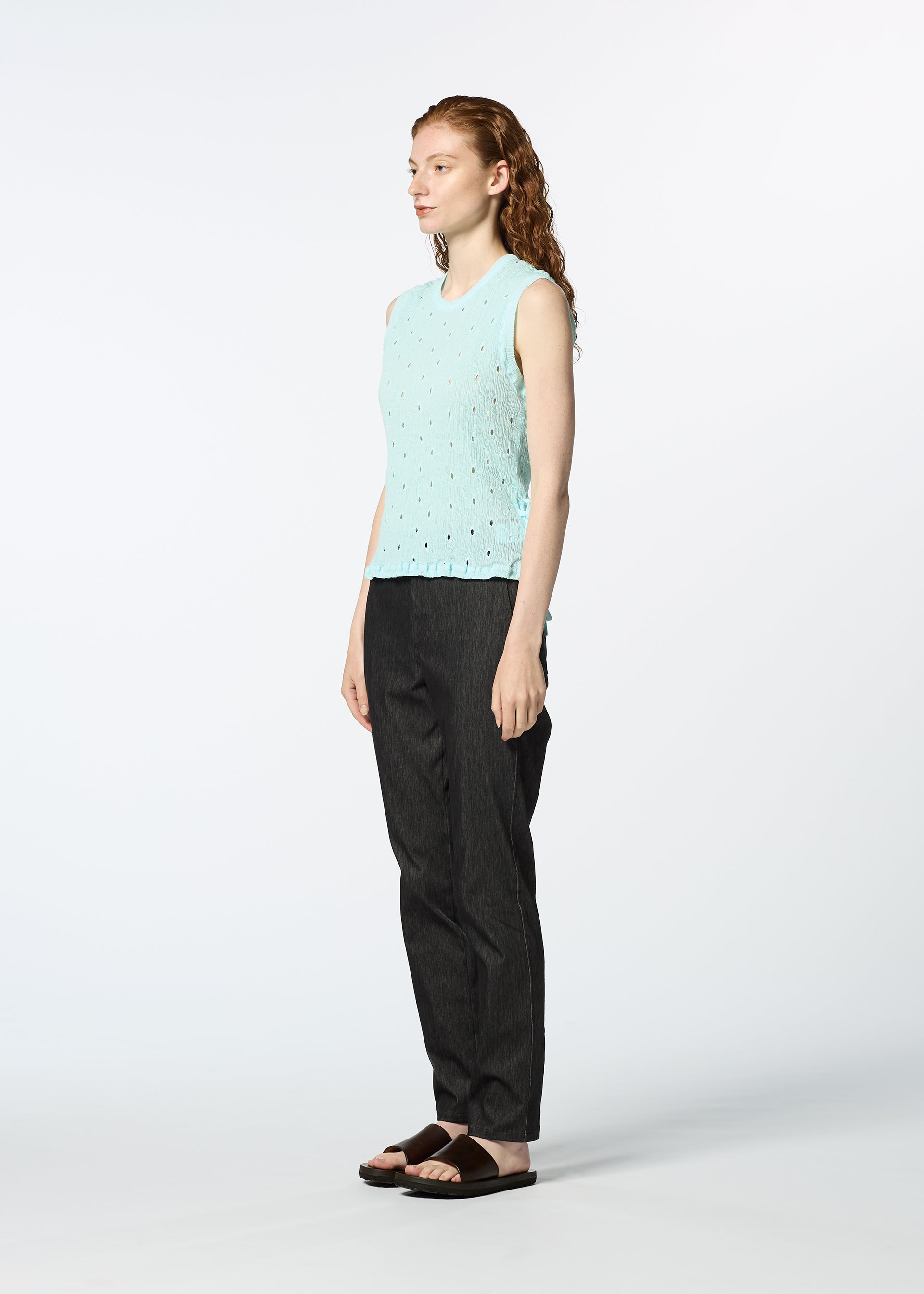Zoomed view A person with long, wavy red hair models the HaaT KYO CHIJIMI TOBIKANNA CADEAU sleeveless top in light blue, paired with dark straight-leg pants and black sandals, standing against a plain white background.