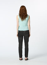 A person with long curly hair, dressed in a light blue HaaT KYO CHIJIMI TOBIKANNA CADEAU sleeveless top, dark pants, and black sandals, stands facing away against a plain white background.