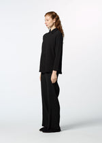 A person with long red hair wears HaaT’s KYO CHIJIMI 2WAY JANUARY 1 set— a loose black long-sleeved shirt and matching wide-leg pants—standing in profile against a plain white background.