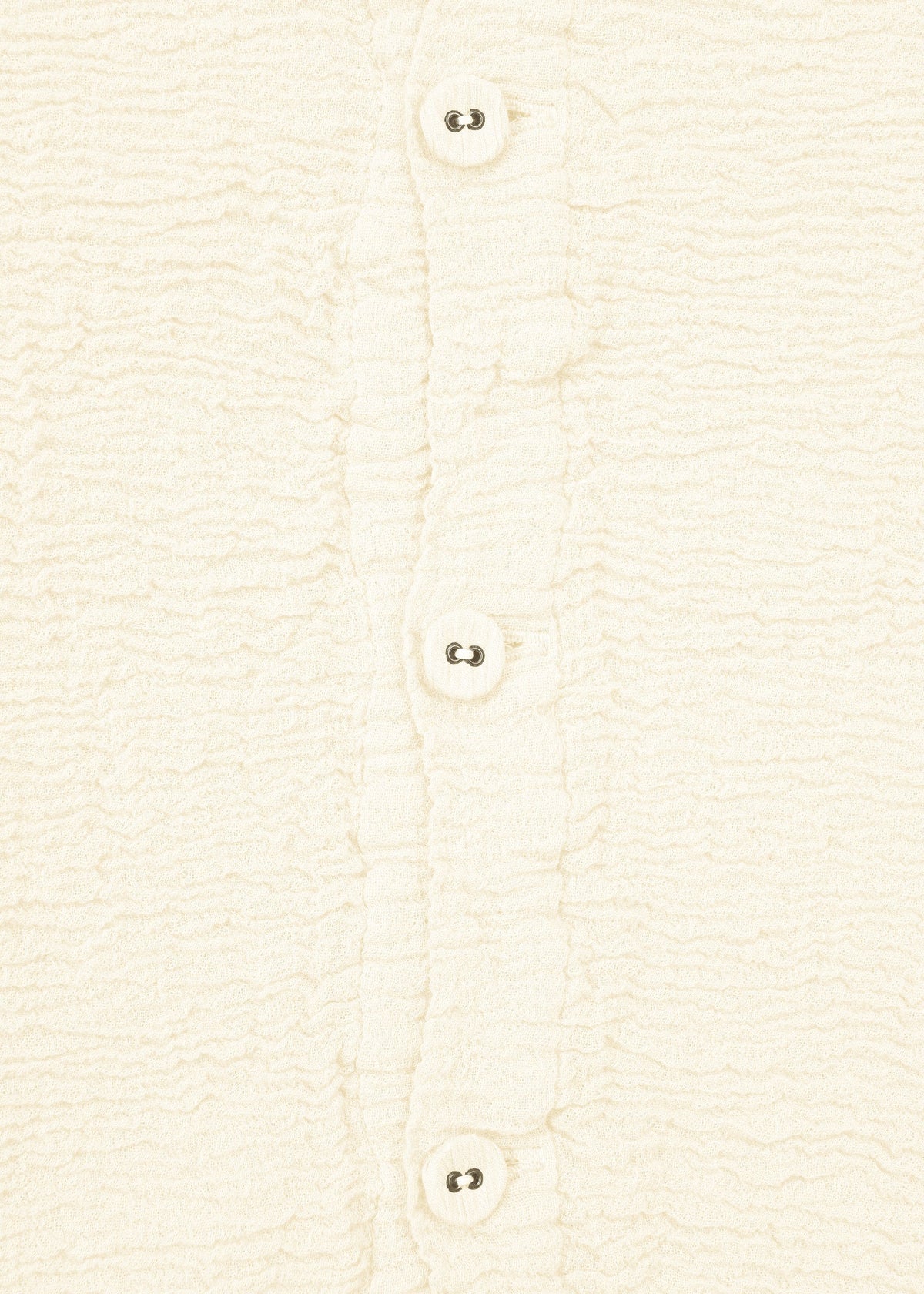 Close-up of HaaT's KYO CHIJIMI 2WAY JANUARY 1 shirt in cream-colored textured fabric, featuring four white buttons, ruffled button placket edges, and unique garment dyeing. view 4 of 8