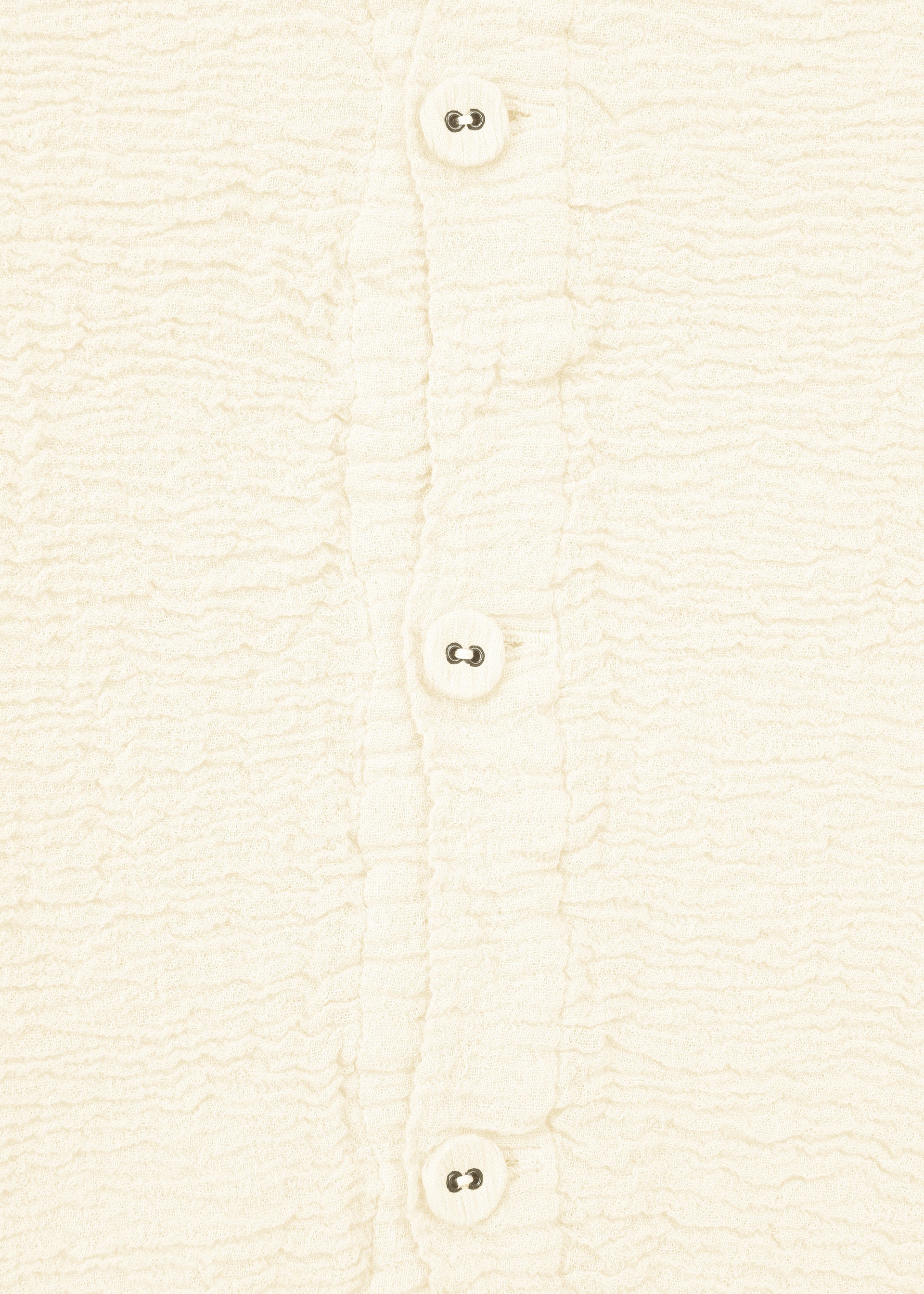 Zoomed view Close-up of HaaT's KYO CHIJIMI 2WAY JANUARY 1 shirt in cream-colored textured fabric, featuring four white buttons, ruffled button placket edges, and unique garment dyeing.