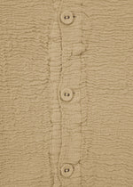 Close-up of KYO CHIJIMI 2WAY JANUARY 2 by HaaT—a beige textured fabric with a wrinkled pattern and a vertical row of four matching buttons, highlighting the unique look from garment dyeing.