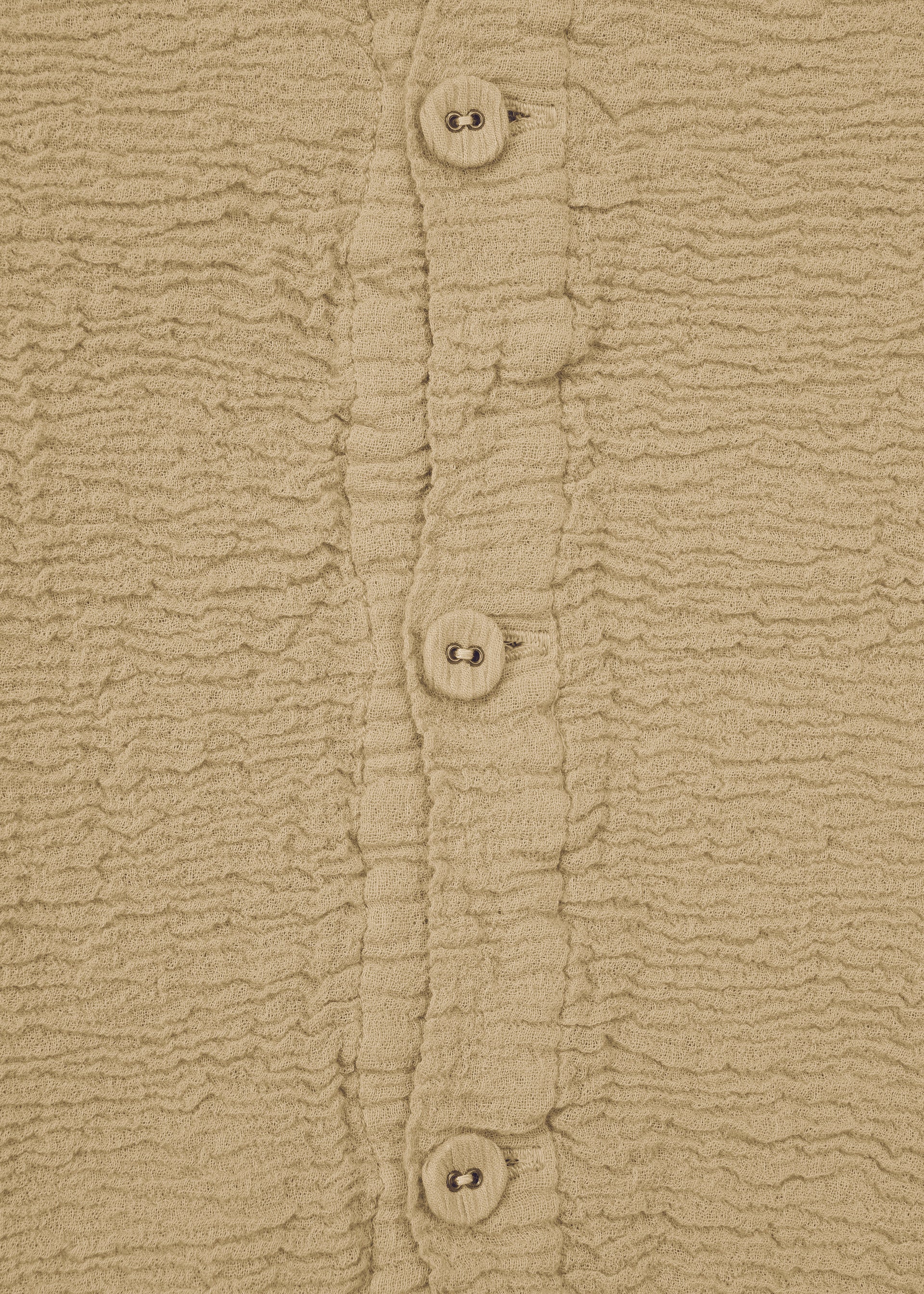 Zoomed view Close-up of KYO CHIJIMI 2WAY JANUARY 2 by HaaT—a beige textured fabric with a wrinkled pattern and a vertical row of four matching buttons, highlighting the unique look from garment dyeing.