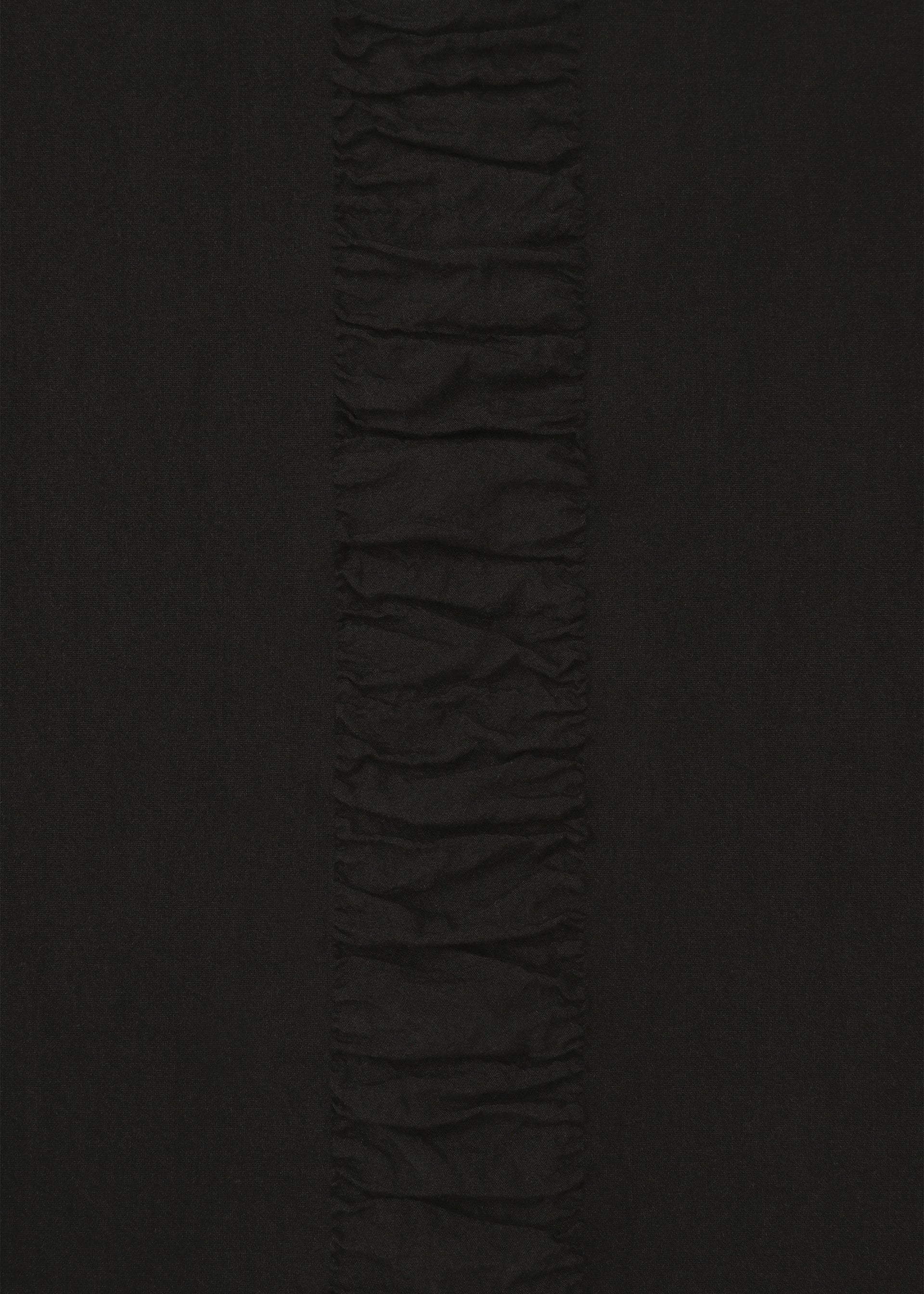 Zoomed view A close-up of HaaT's TENMOKU COTTON shows black, garment-dyed long-sleeve fabric with a vertical ruched strip down the center, creating textured contrast against the smoother fabric on each side.