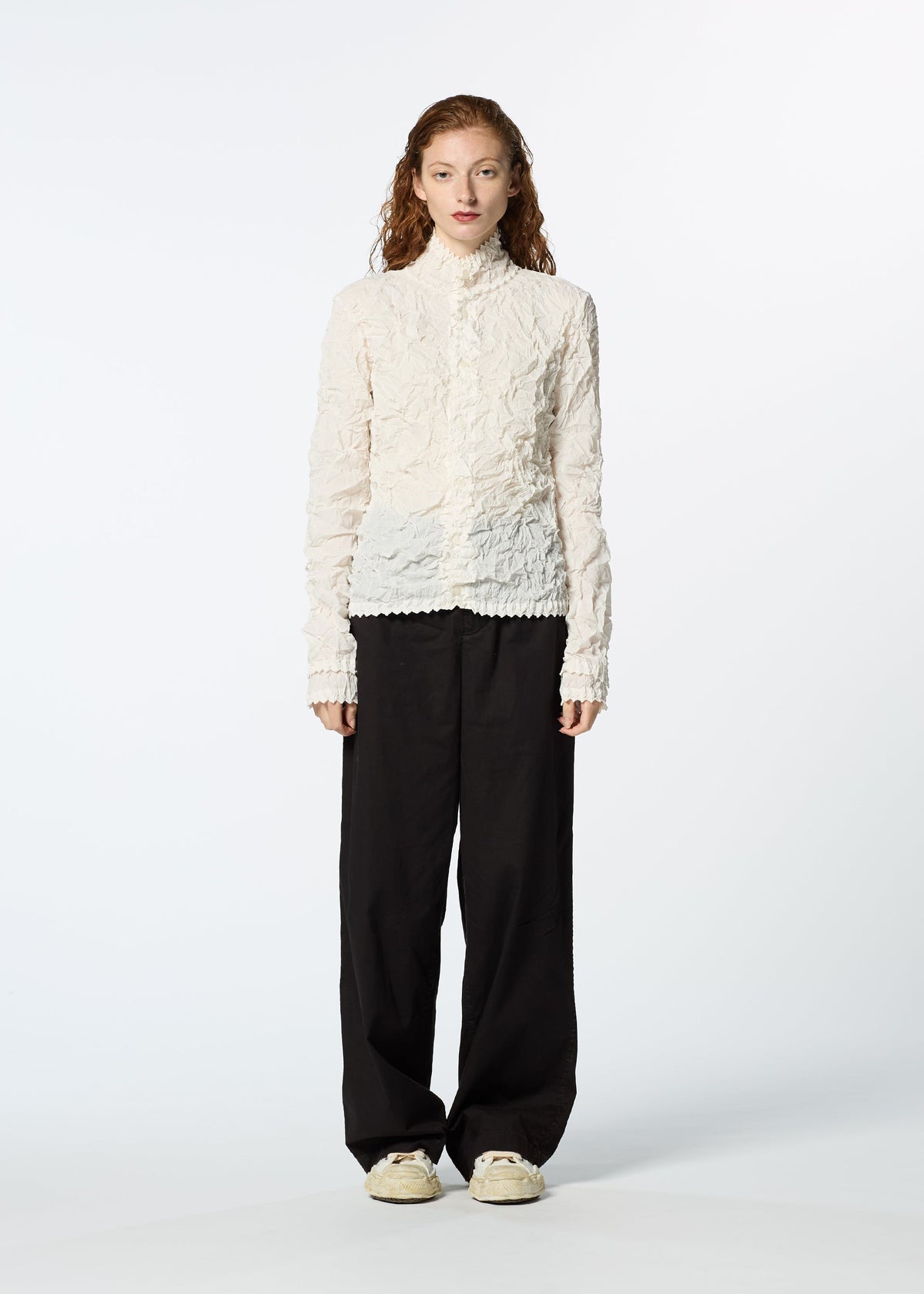 A person with long, wavy hair faces forward in a textured white long-sleeve top layered under the HaaT KUMO SHIBORI SHIRT, paired with loose black pants and off-white sneakers, set against a plain light background. view 7 of 9