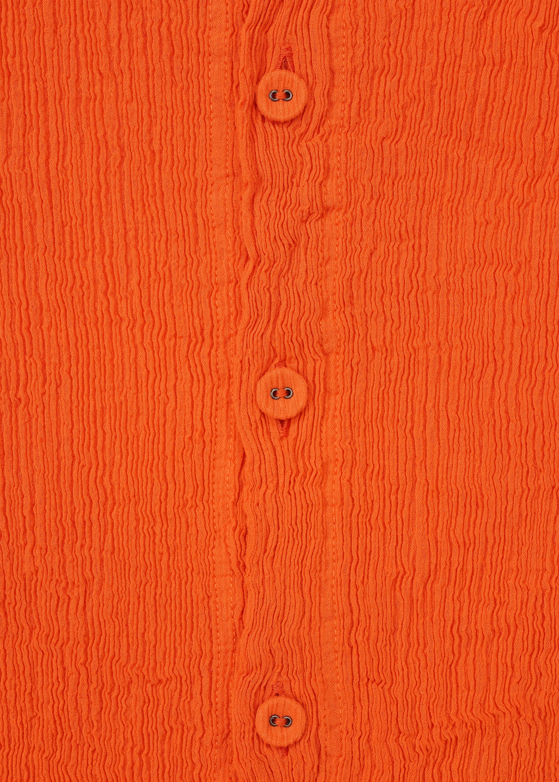 Zoomed view Close-up of the orange KYO CHIJIMI MAY cardigan by HaaT, crafted from ultra-fine cotton yarn with four matching buttons, a round neck, long sleeves, wavy textured fabric, and visible stitching.