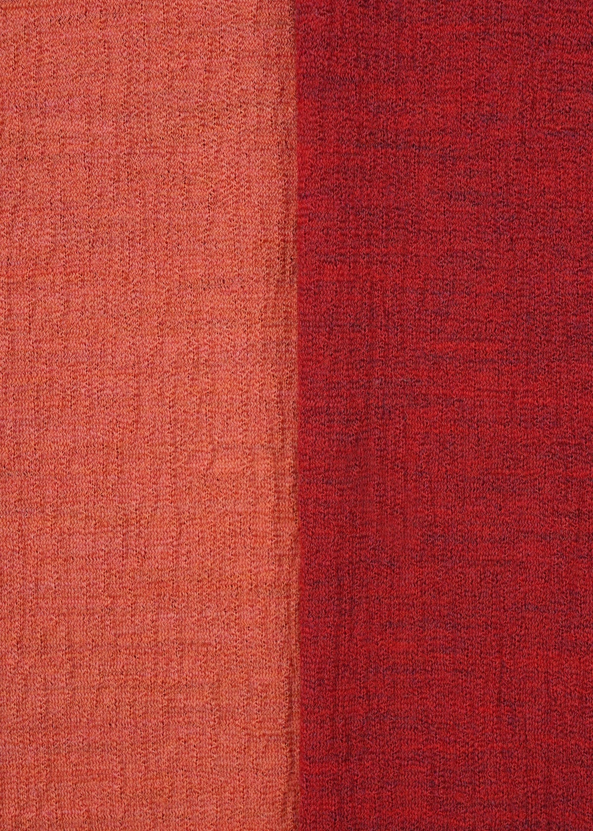 Close-up of HaaT's TRI COLOR WOOL fabric: vertically split with light orange-red on the left, deeper red on the right. Both textured sides have a woven, slightly rough look—ideal for relaxed merino wool or multicolor jersey pants. view 9 of 13