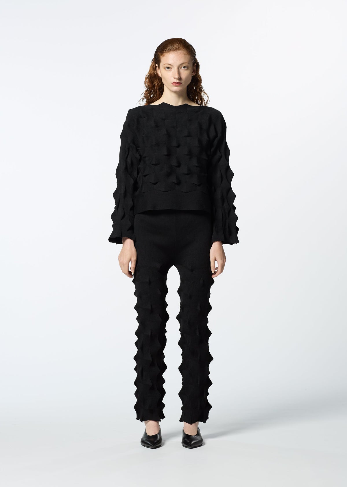 A woman wearing HaaT's ZIG ZAG KNIT pants crafted from recycled polyester in a black outfit. view 5 of 7