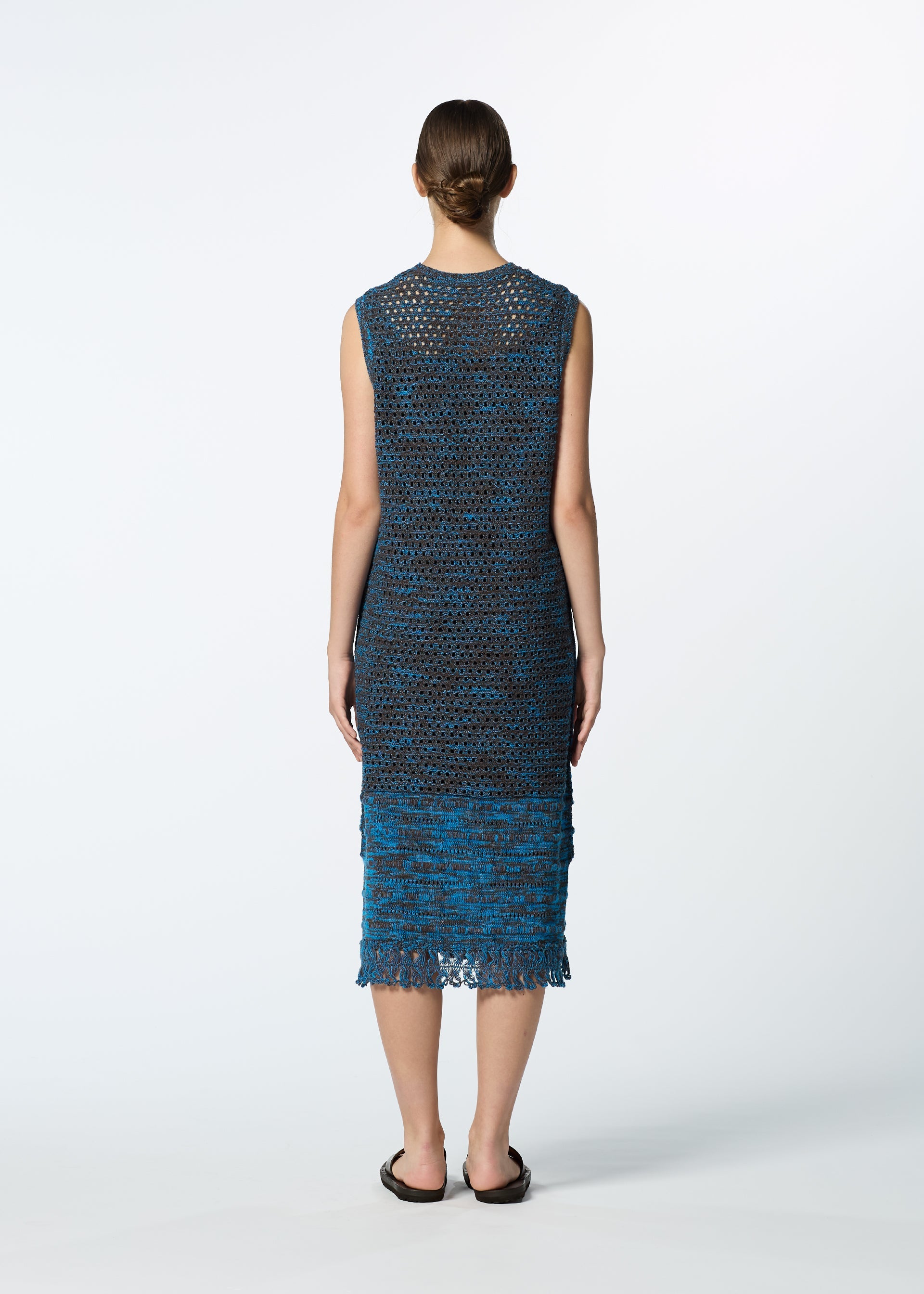 Zoomed view A person with hair tied back, wearing the HaaT MELANGE MESH sleeveless, knee-length blue knit dress and black sandals, stands facing away against a plain white background.