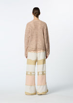 A person faces away, wearing HaaT's MELANGE MESH light pink mesh lace long-sleeve top and wide-legged, textured color-blocked pants in cream, beige, and blush. The background is plain white.