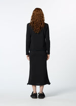 A person with long curly red hair, wearing HaaT's PLATED LINES black lightweight knit top and black midi skirt, stands facing away from the camera against a plain white background.