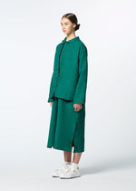 A person with brown hair tied back wears HaaT’s DUAL LAYER handwoven cotton jacket with Kabira embroidery and a matching teal midi skirt, paired with white sneakers—celebrating Indian artisanship against a plain light background.