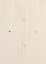 Close-up of the DUAL LAYER jacket by HaaT—a cream quilted, handwoven cotton piece featuring vertical stitches, three fabric-covered buttons, and two small embroidered eyelets by Indian artisans beside the button placket.