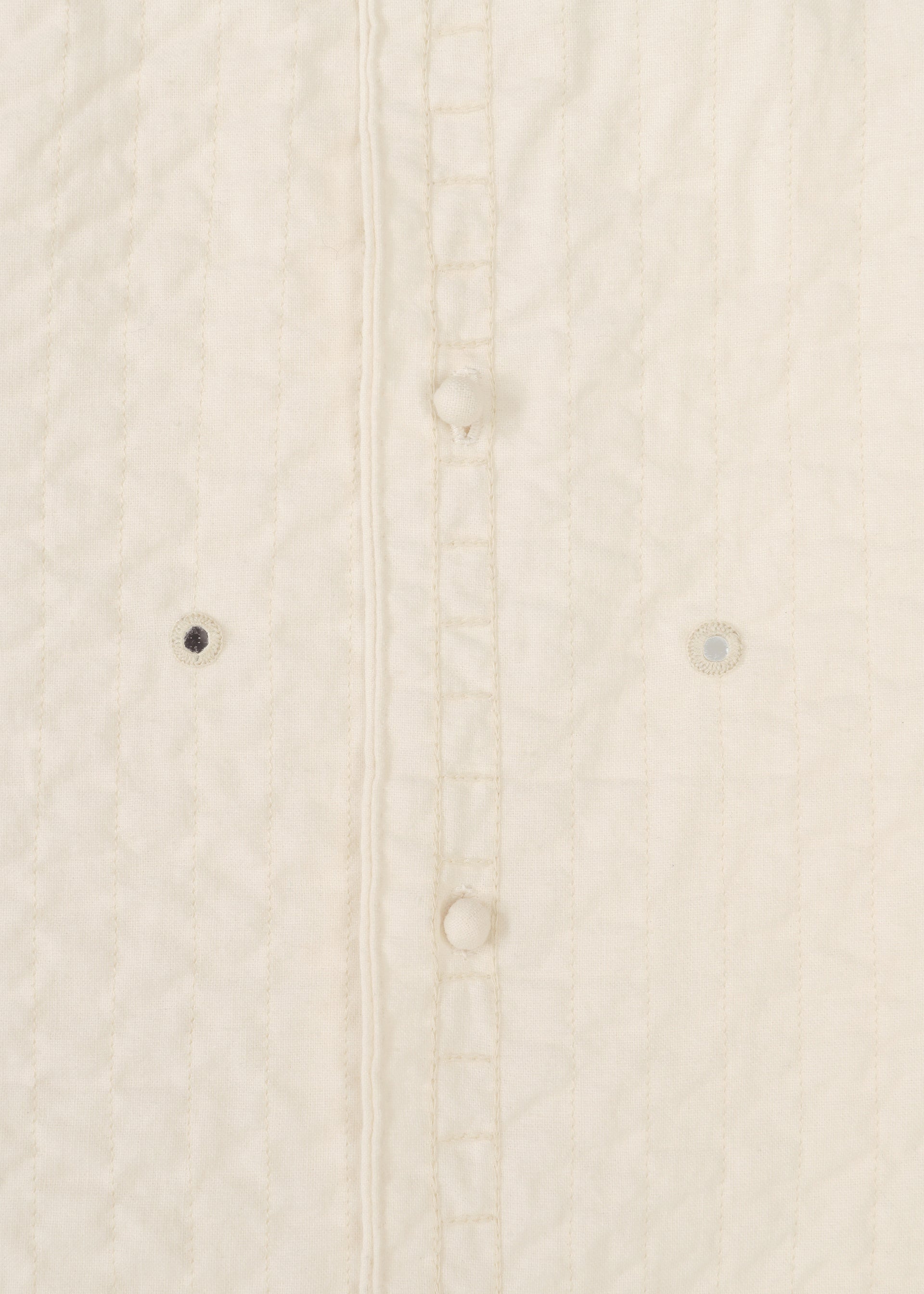 Zoomed view Close-up of the DUAL LAYER jacket by HaaT—a cream quilted, handwoven cotton piece featuring vertical stitches, three fabric-covered buttons, and two small embroidered eyelets by Indian artisans beside the button placket.