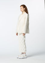 A person with long curly hair stands in profile wearing HaaT's GLASSLEAF off-white textured blazer with Bhill embroidery, matching pants, and white sneakers against a plain light background.