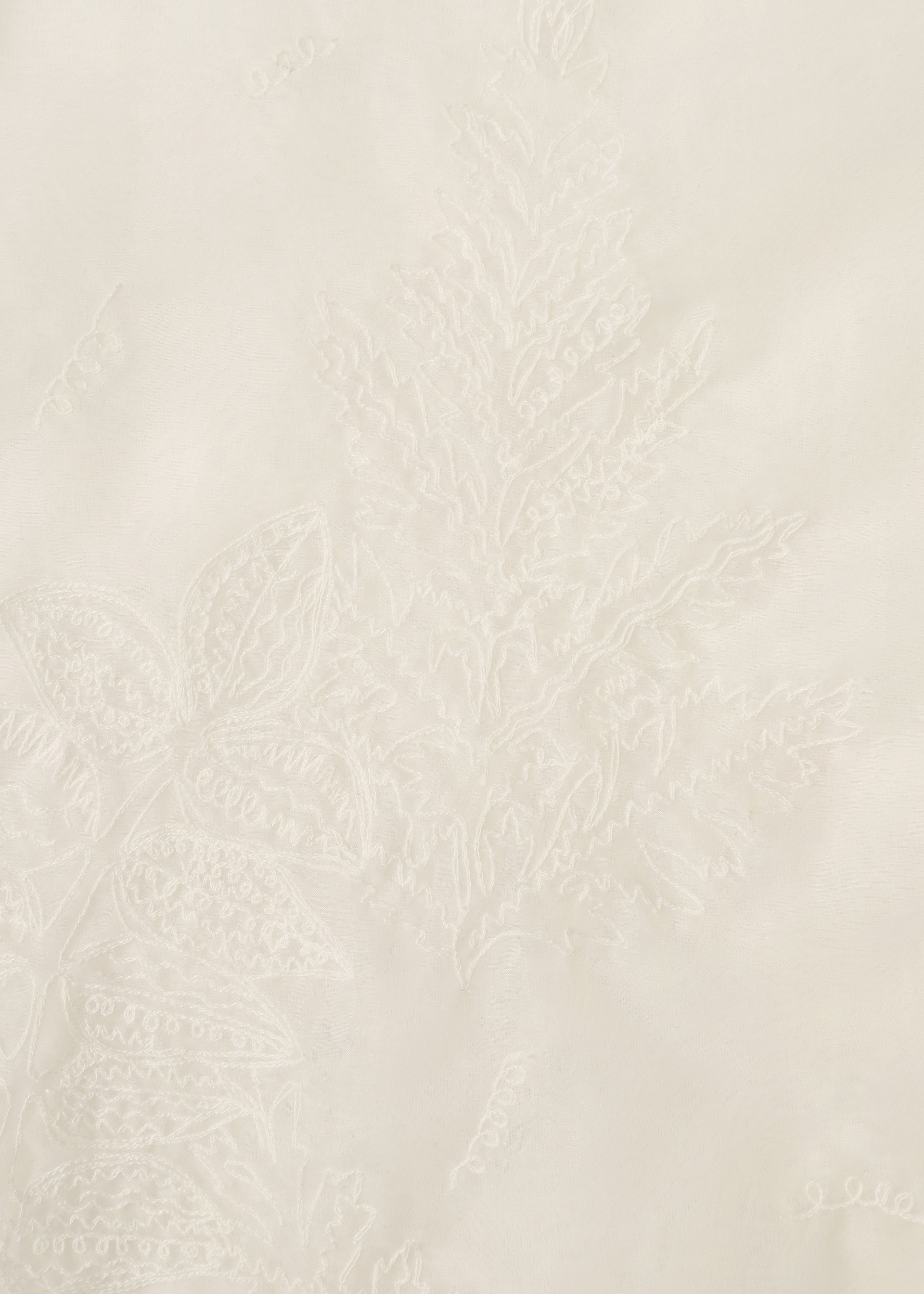 Zoomed view Close-up of GLASSLEAF by HaaT: white fabric featuring delicate Bhill embroidery with a subtle fern and leaf motif, creating a textured, monochromatic botanical design on a smooth surface.