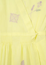 Close-up of HaaT's DAMI LEAVES: a handmade Indian dress in light yellow with intricate purple geometric and floral embroidery, gathered pleats, and a fabric-covered button detail.