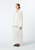 A person stands against a plain background wearing HaaT's DAMI LEAVES set: a loose, long-sleeve white shirt and matching long skirt with subtle Chikan embroidery. Their brown hair is pulled back, paired with black sandals.