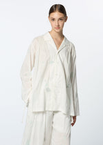 A young woman with brown hair tied back wears the DAMI LEAVES set by HaaT—a relaxed, pajama-style outfit with subtle Chikan embroidery and wide-leg pants, contrasting against a plain, light background.