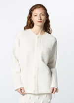 A woman with wavy red hair models HaaT's 3 MUL MACHINE KABIRA '26SS: a textured white collarless shirt and matching skirt with subtle Indian embroidery, set against a simple light background.