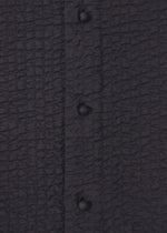 Close-up of black fabric with four fabric-covered buttons. The crinkled texture recalls Indian embroidery, adding depth and pattern to the collarless 3 MUL MACHINE KABIRA '26SS shirt by HaaT.