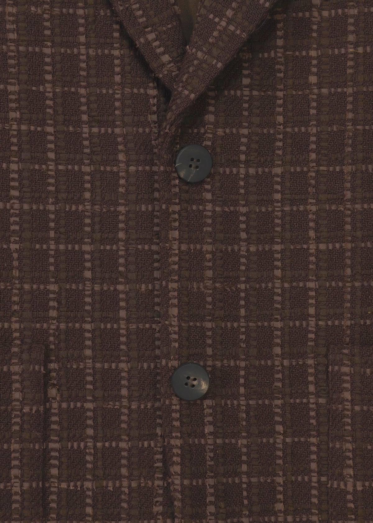 Zoomed view Close-up of the SAKIORI blazer by HaaT in brown textured grid-patterned fabric with two black buttons fastened, highlighting traditional weaving on the front torso and part of the collar.