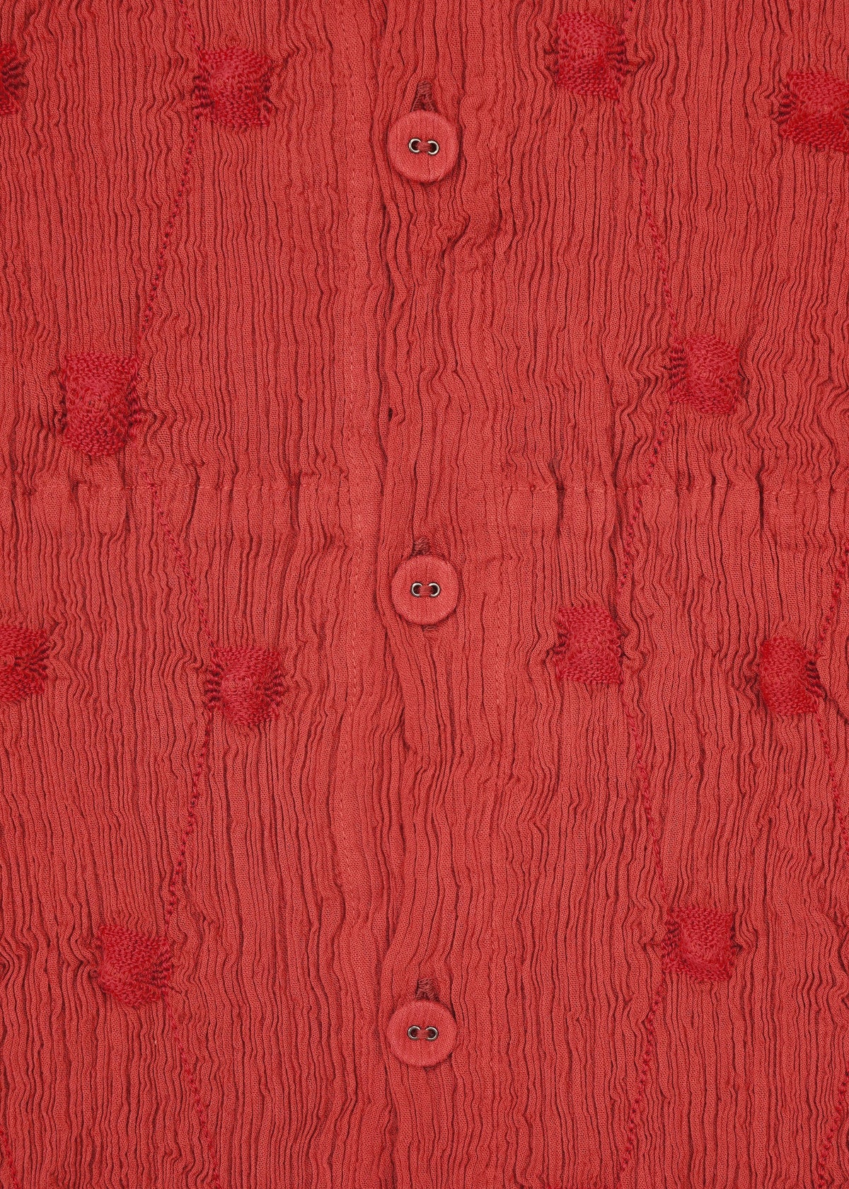 Close-up of HaaT’s KYO CHIJIMI SQUARE EMB fabric in textured red, featuring ruched patterns, round buttons at the center, and evenly spaced tufted circular details, all accented by subtle square embroidery inspired by traditional KYO CHIJIMI craftsmanship. view 6 of 10