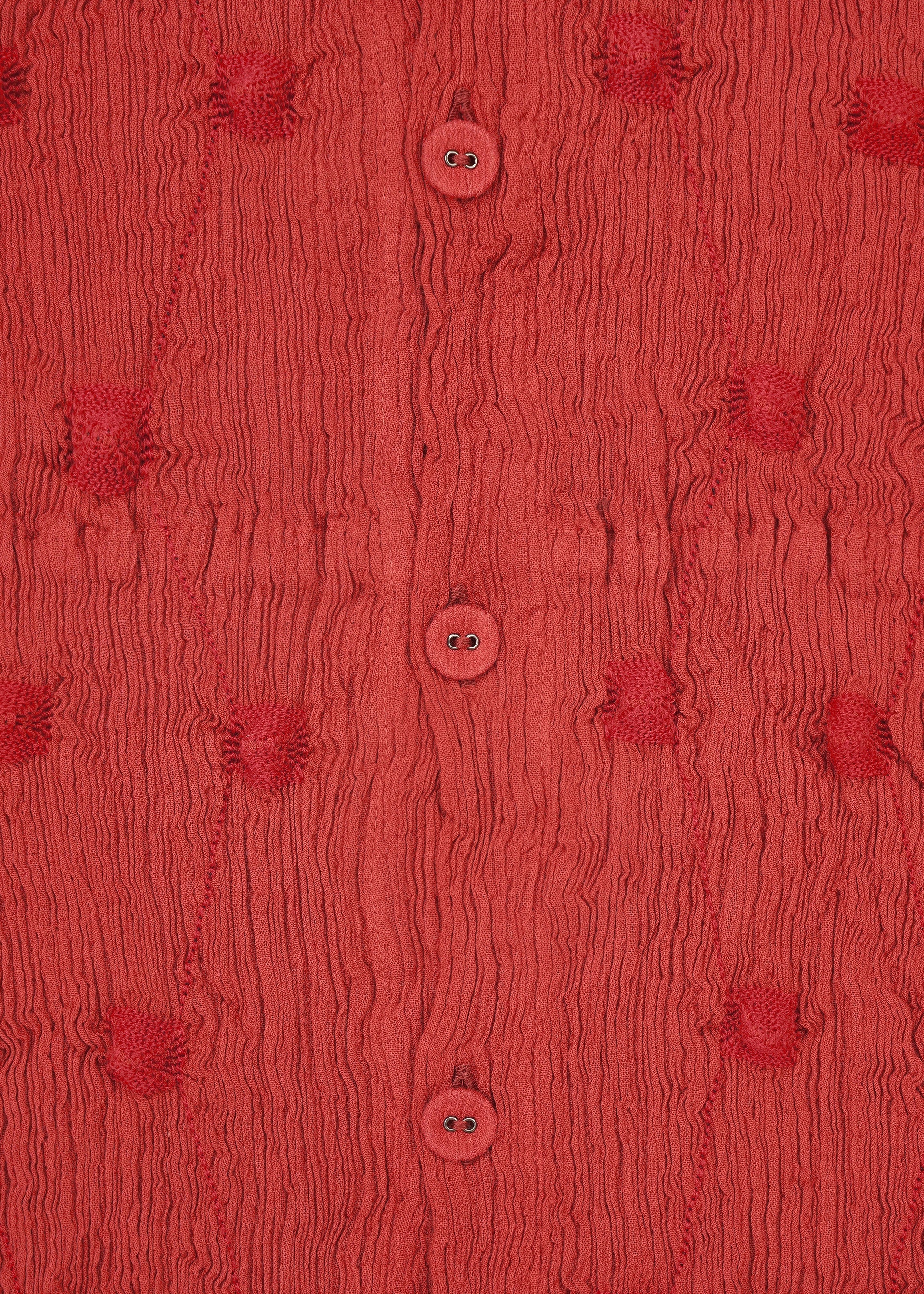 Zoomed view Close-up of HaaT’s KYO CHIJIMI SQUARE EMB fabric in textured red, featuring ruched patterns, round buttons at the center, and evenly spaced tufted circular details, all accented by subtle square embroidery inspired by traditional KYO CHIJIMI craftsmanship.